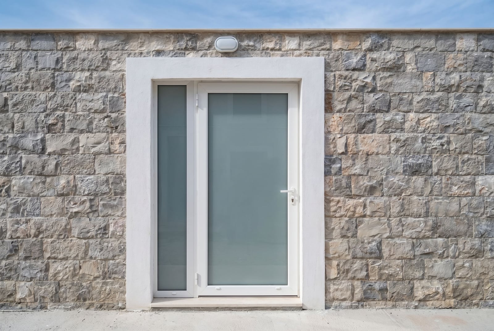 Entrance to the apartment in Đenovići, Montenegro: a white plastic door with frosted glass against a stone facade.
