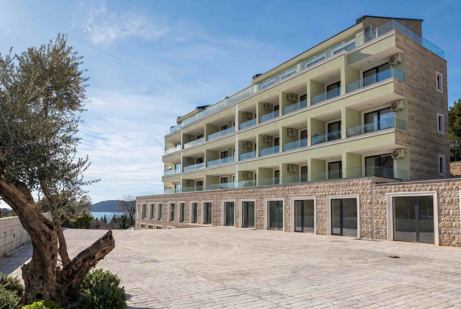 Modern residential complex in Pržno, Montenegro: facade with balconies, panoramic glazing, and sea view.