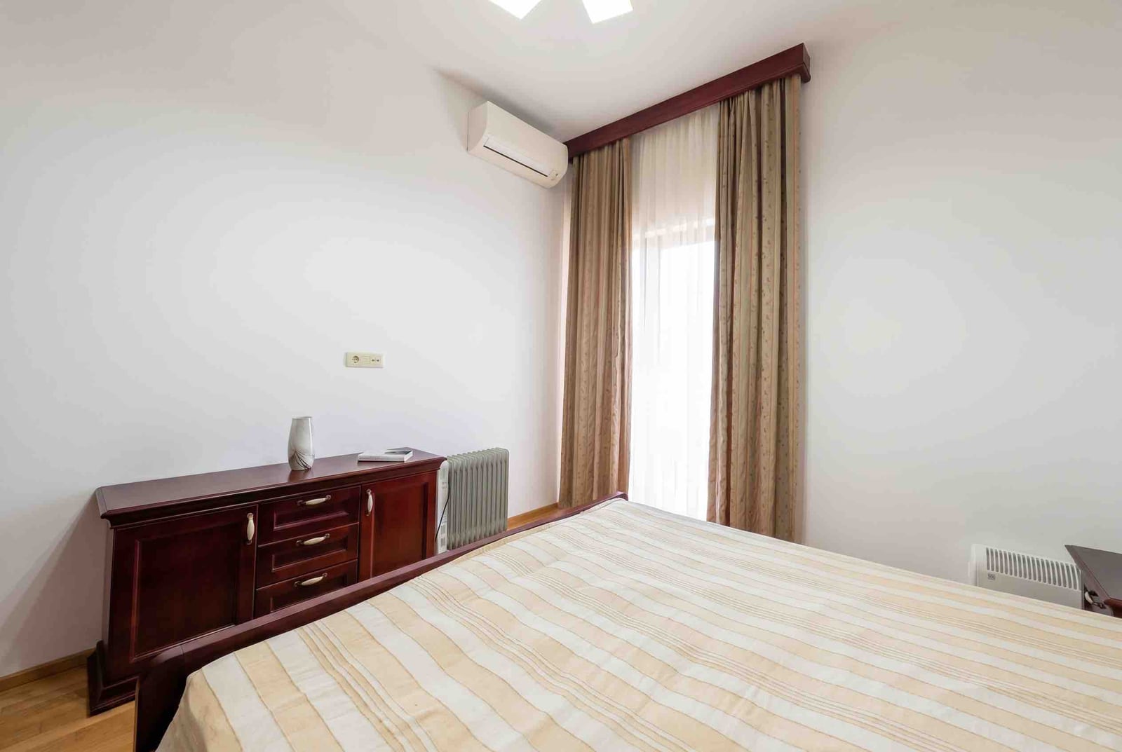 Bright bedroom with a double bed and chest of drawers in an apartment in Bečići, Montenegro, with access to a balcony and air conditioning.