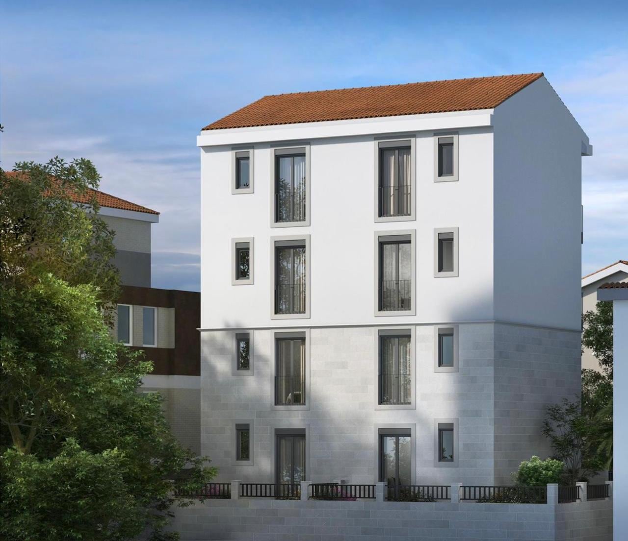 Modern residential complex in Herceg Novi, Montenegro: a three-story building with stone cladding and a tiled roof.