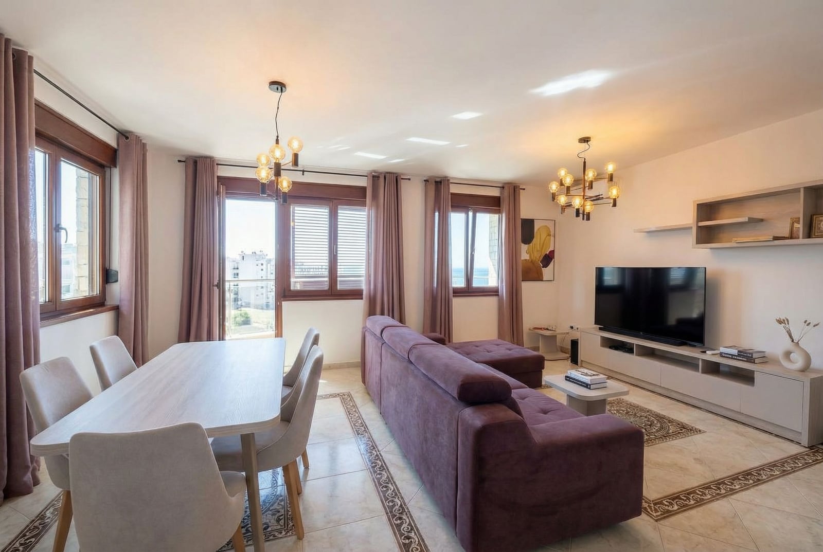 Bright living room with a purple sofa and dining area in an apartment in Rafailovići, Montenegro, sea view.