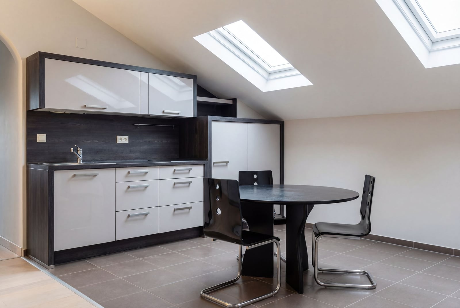 Modern attic kitchen in a house in Herceg Novi, Montenegro: glossy cabinetry, dining area, and skylight windows.