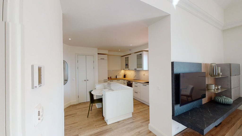 Modern living room with kitchen and island in an apartment, Luštica, Montenegro: bright interior, TV area, and decor.