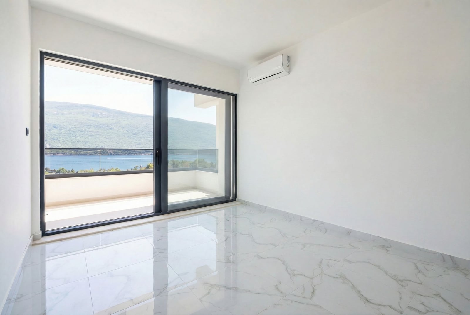 Bright living room in an apartment in Kumbor, Montenegro: panoramic windows, sea view, marble floor, and air conditioning.