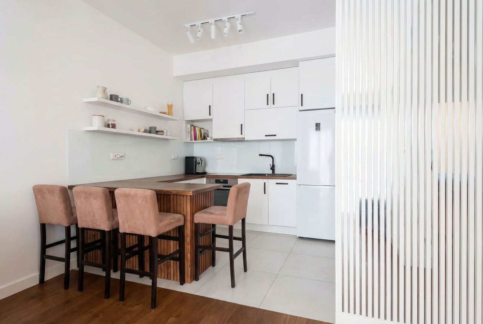 Modern kitchen with a breakfast bar in an apartment, Bar, Montenegro: white cabinets, wooden countertop, and decor.