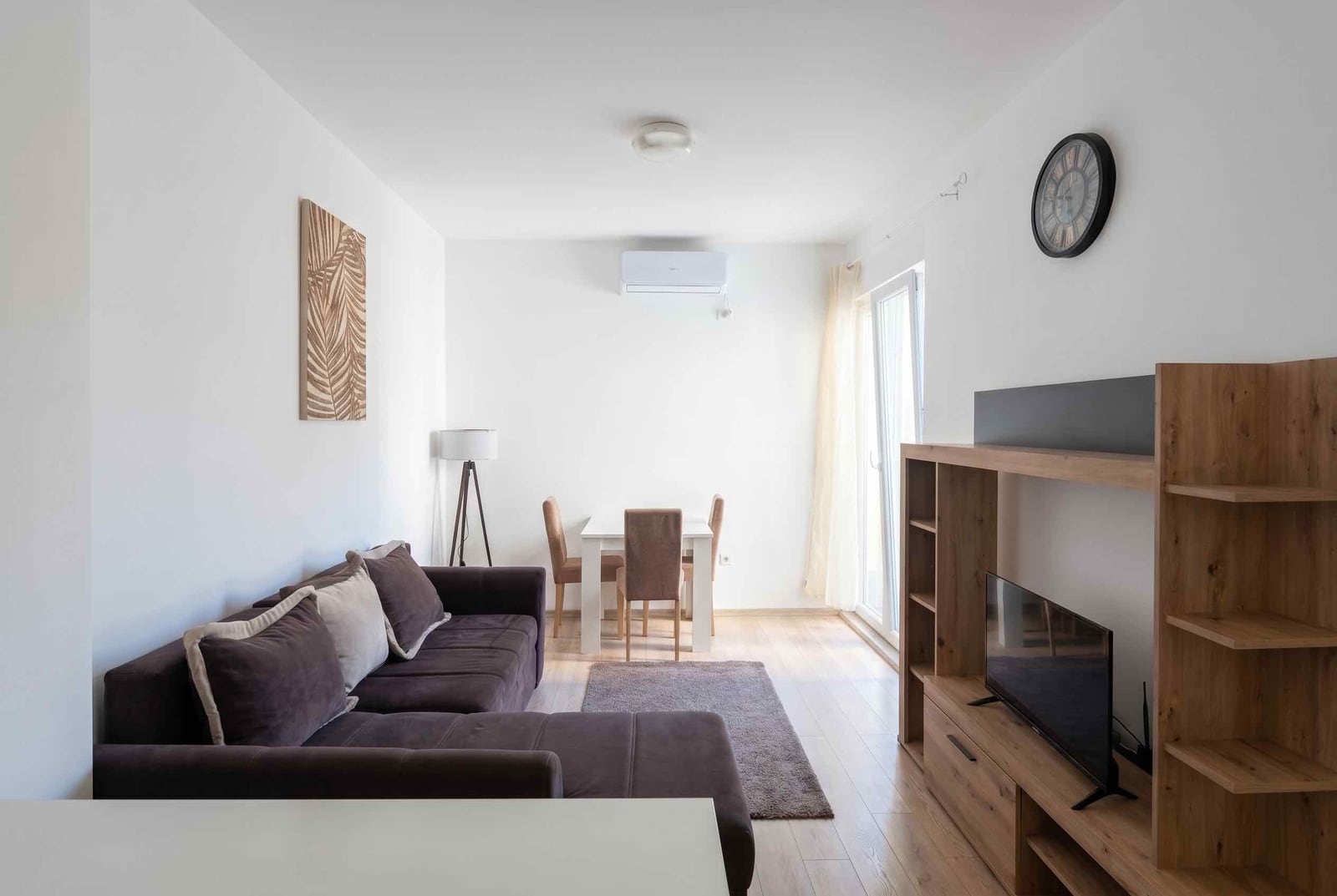 Bright living room with a brown sofa and dining area in an apartment, Budva, Montenegro. Modern interior.