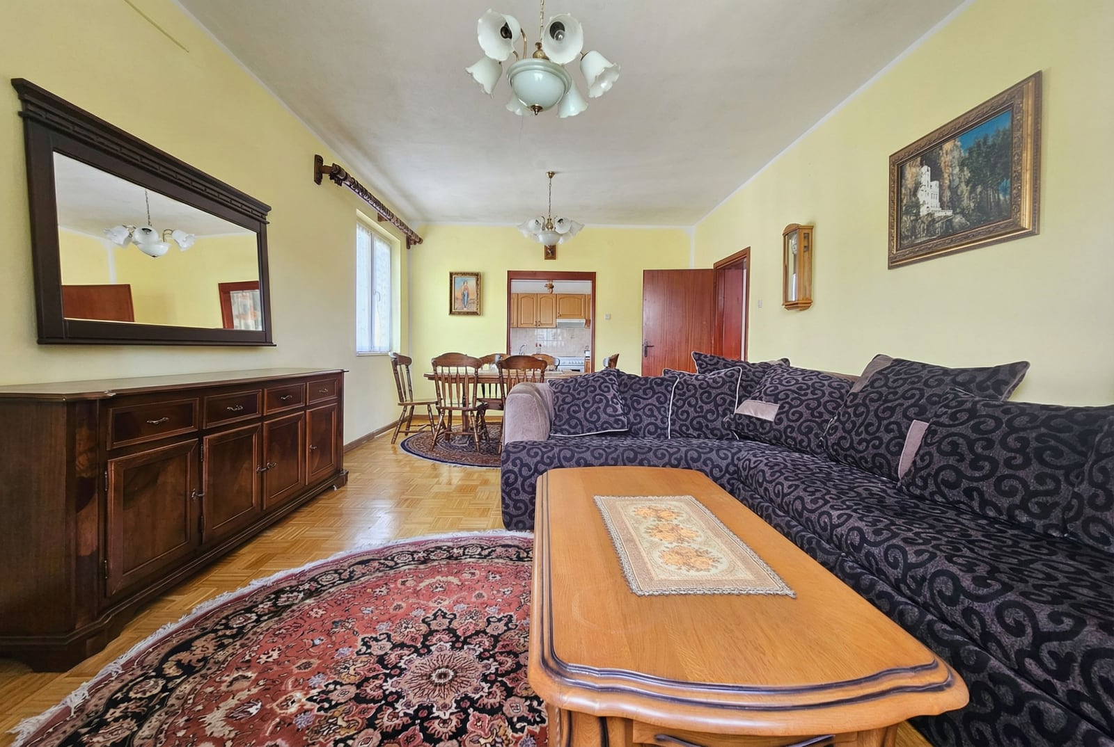Spacious living room with a dark sofa and dining area in a house, Herceg Novi, Montenegro. Parquet flooring and classic furniture.