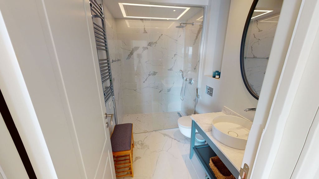 Modern bathroom with marble finish in an apartment at Luštica Bay, Montenegro: shower, round mirror.