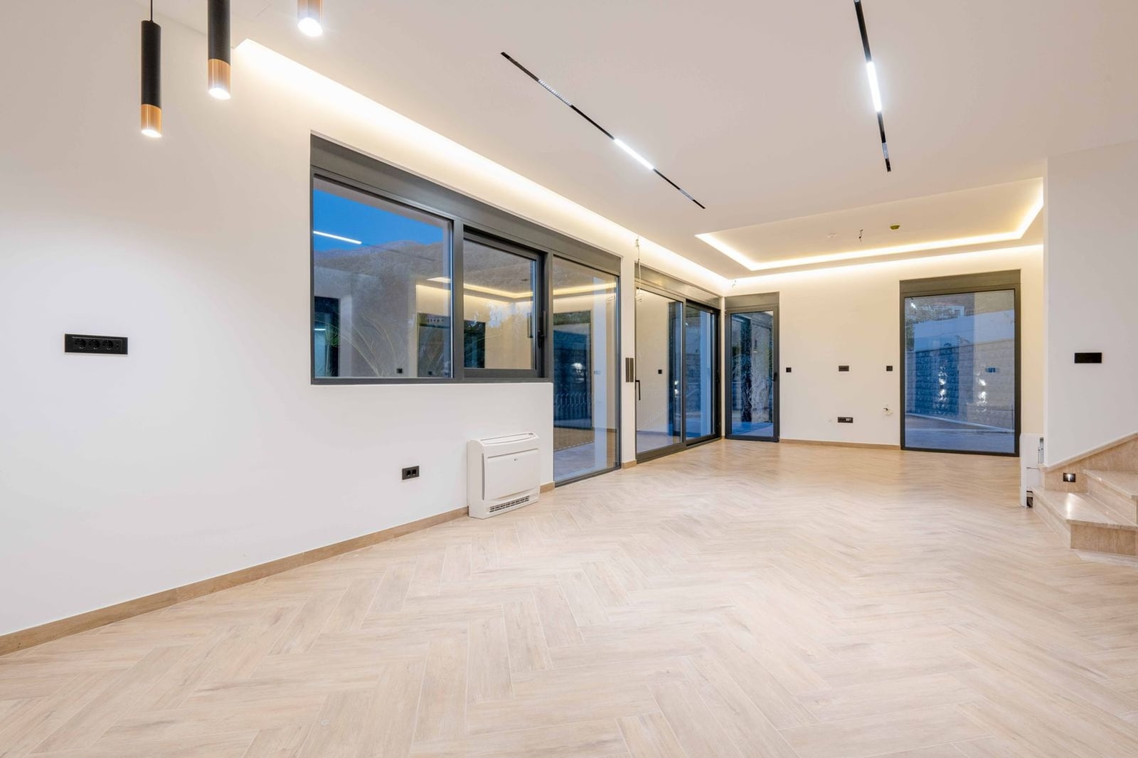 Salon spacieux avec baies vitrées panoramiques et parquet en point de Hongrie dans une villa à Kamenovo, Monténégro. Intérieur moderne.