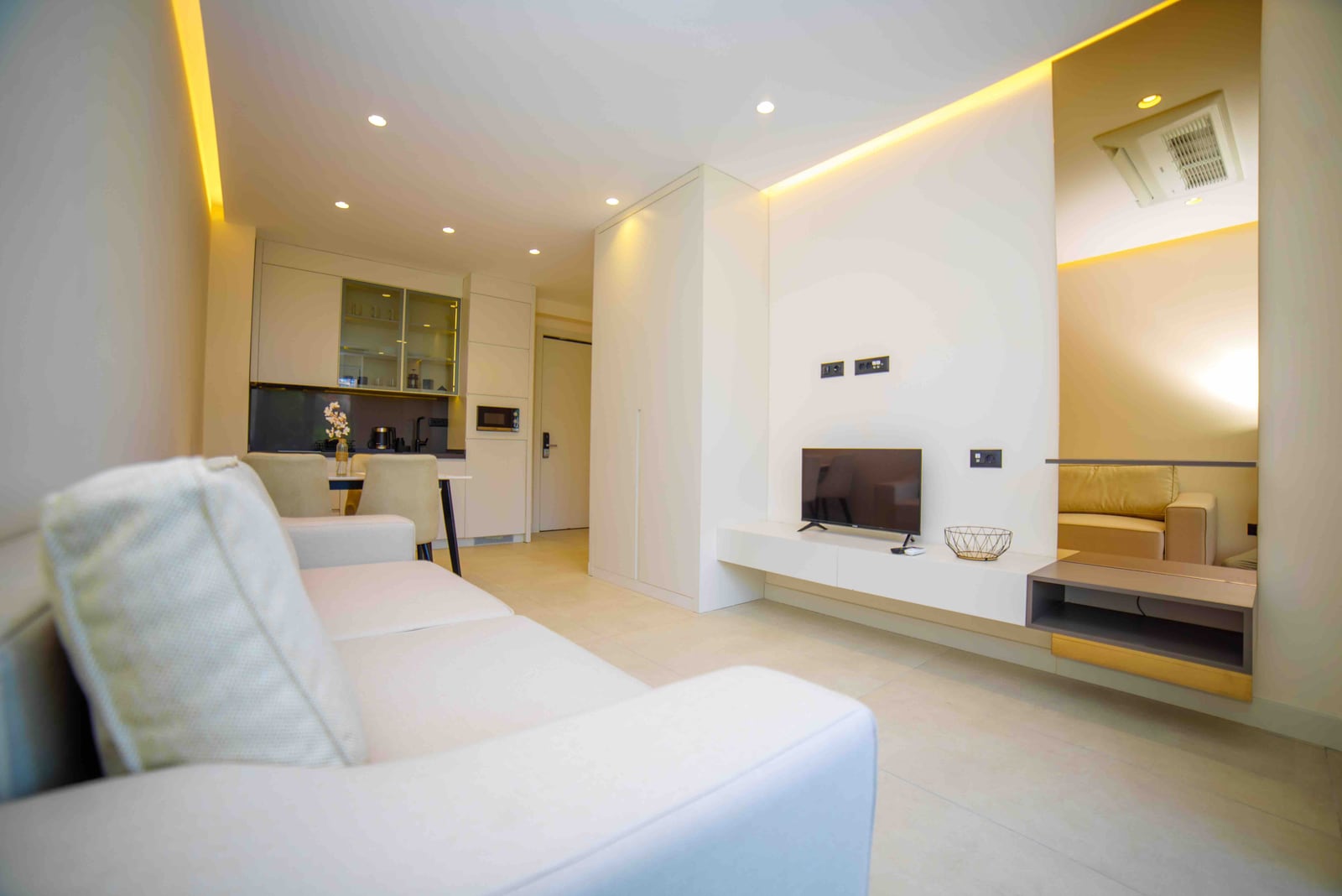 Modern living room with kitchen in an apartment in Bečići, Montenegro: bright interior, upholstered furniture, and built-in appliances.