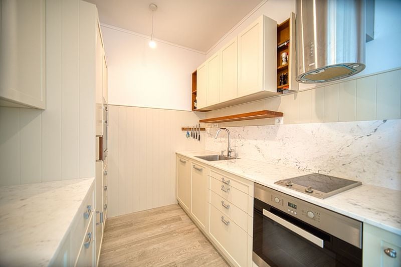 Modern bright kitchen in an apartment, Luštica, Montenegro: marble countertop, built-in appliances, and white facades.
