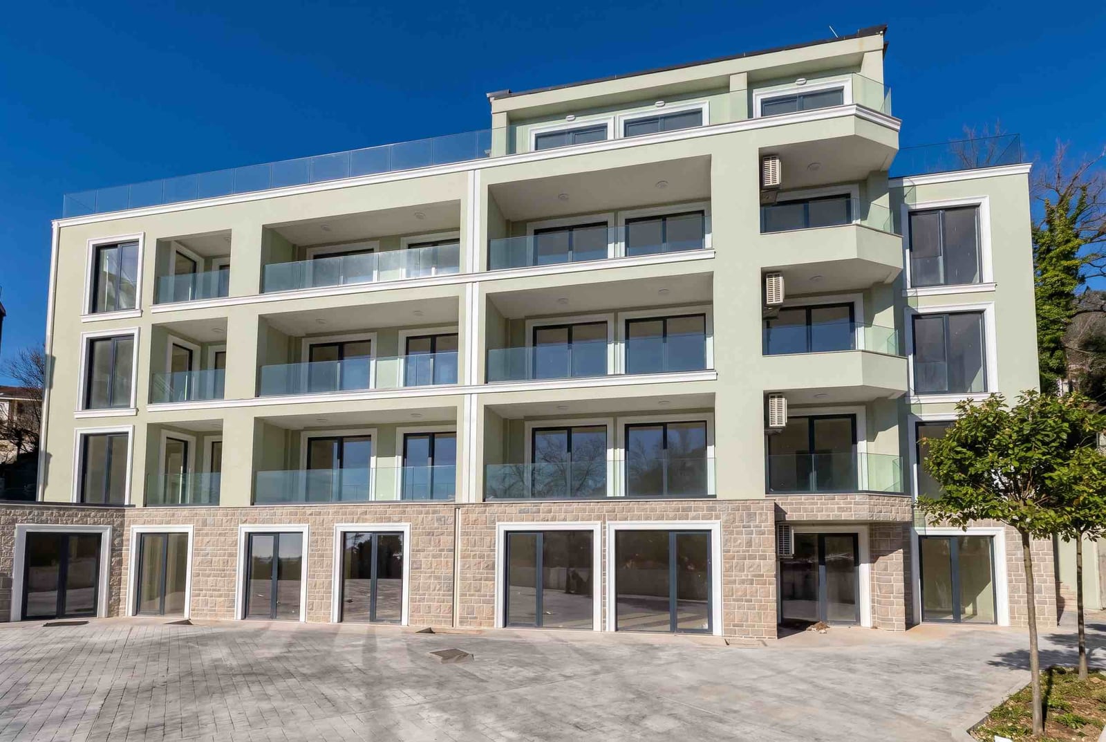 Modern residential complex with terraces in Pržno, Montenegro: building facade with panoramic windows and stone cladding.
