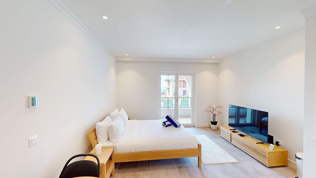 Bright bedroom with wooden furniture and balcony access in Lustica Bay apartments, Montenegro.