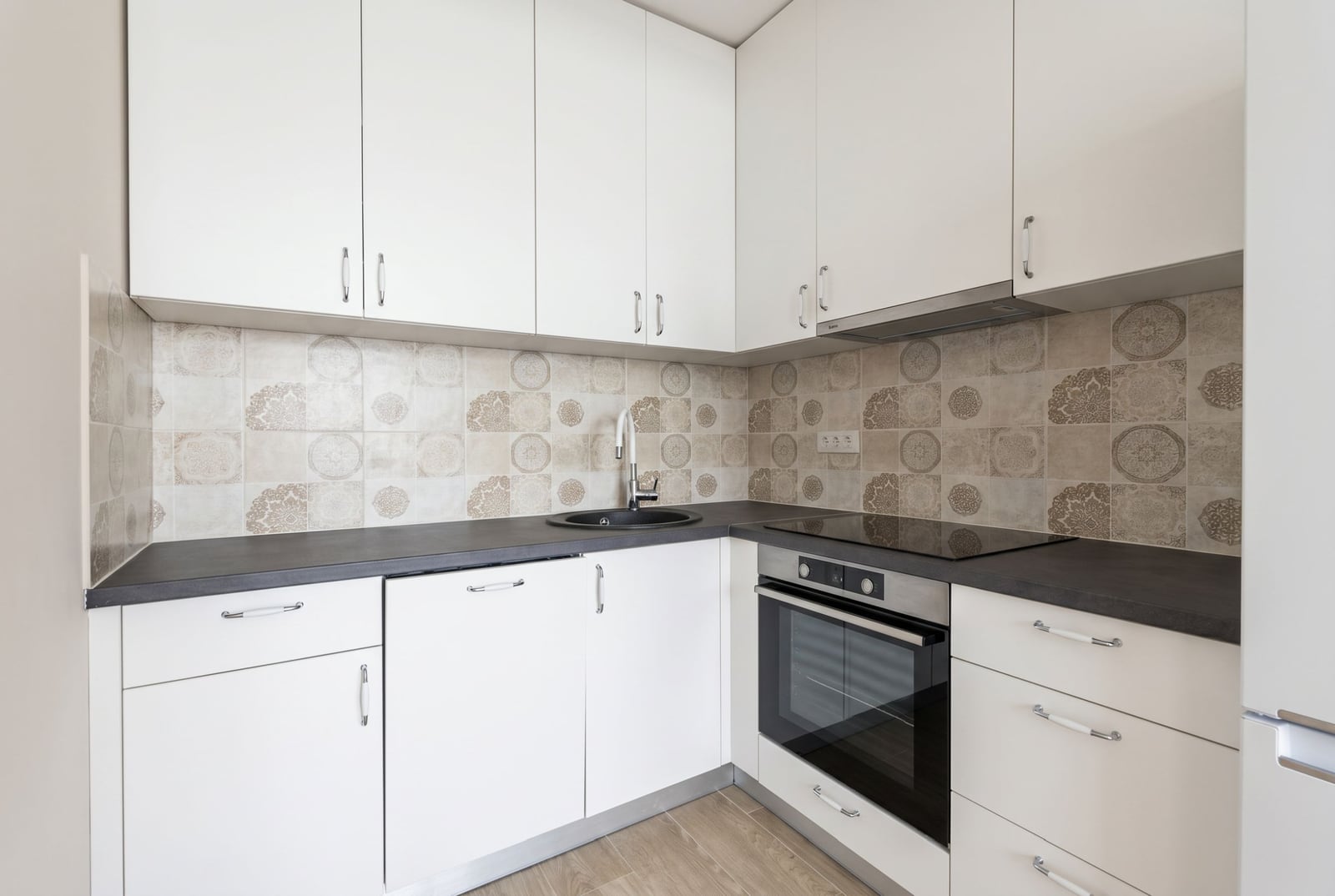 Modern white kitchen with a dark countertop and patterned backsplash in an apartment, Herceg Novi, Montenegro.