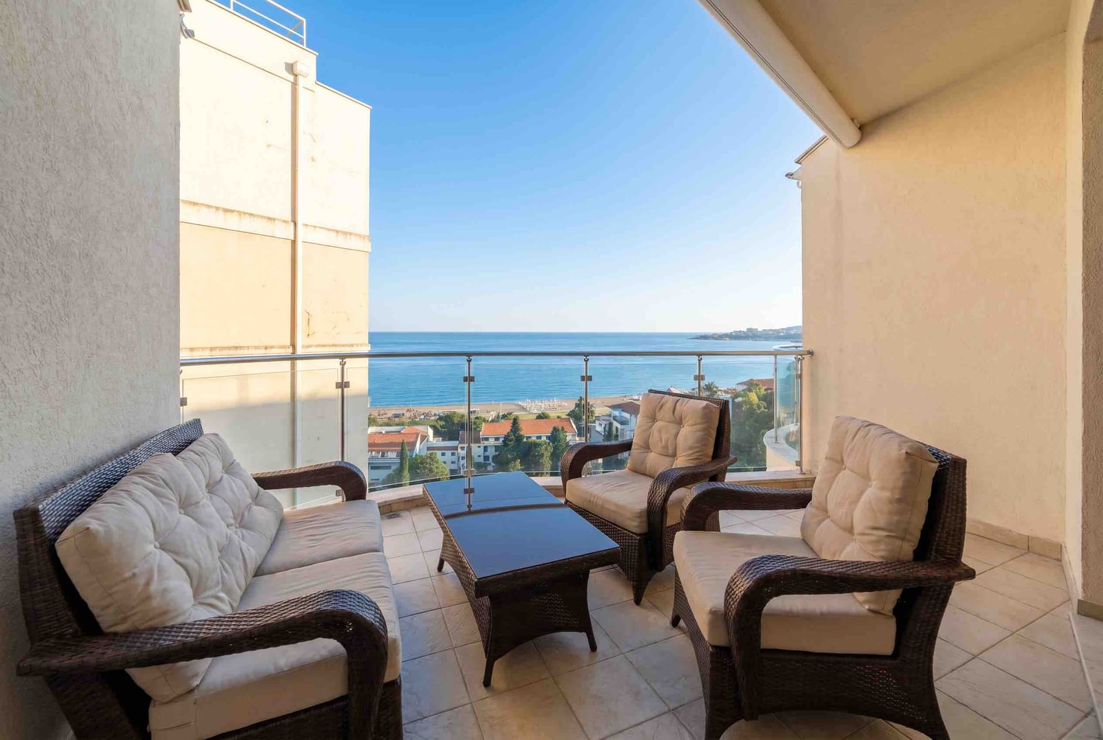 Balcony with wicker furniture and panoramic sea view in a residential complex in Bečići, Montenegro.