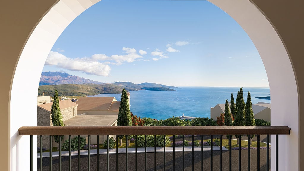 View from the arched balcony overlooking the sea, mountains, and coastal villas in the Luštica residential complex, Montenegro.