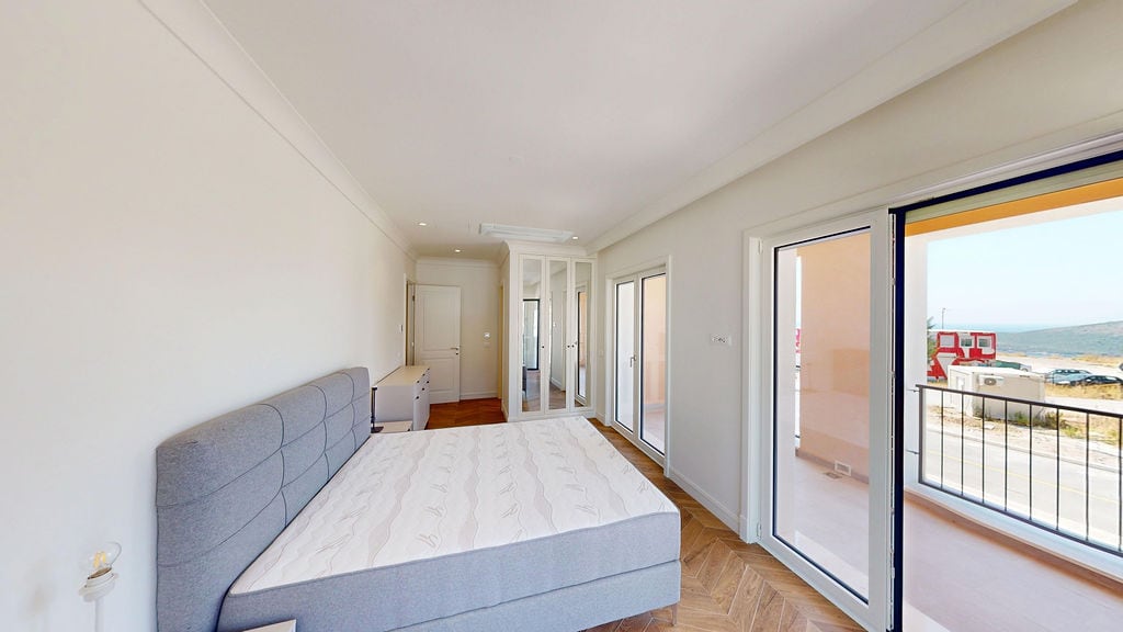 Bright bedroom with a double bed, mirrored wardrobe, and balcony access in an apartment in Luštica, Montenegro.