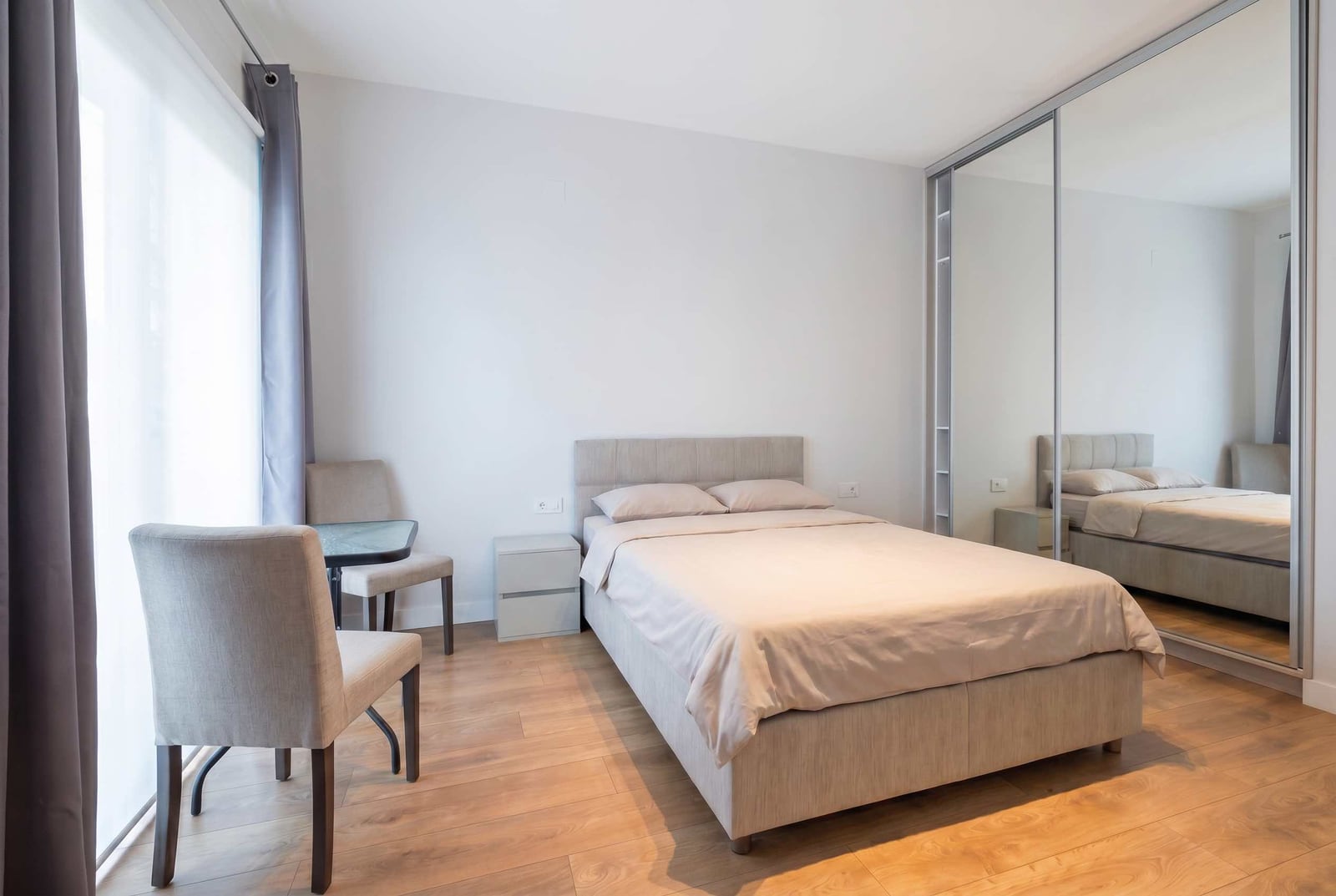 Bright bedroom in an apartment, Kavač, Montenegro: double bed, mirrored wardrobe, and a table with chairs.
