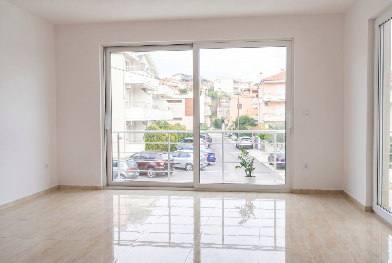 Bright living room with a panoramic window and glossy floor in an apartment in Herceg Novi, Montenegro. View of the city street.