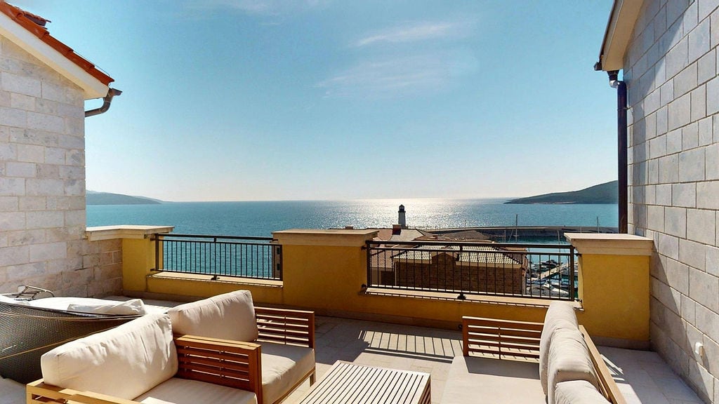 Terrace with furniture and panoramic view of the sea and marina in the Luštica residential complex, Montenegro.
