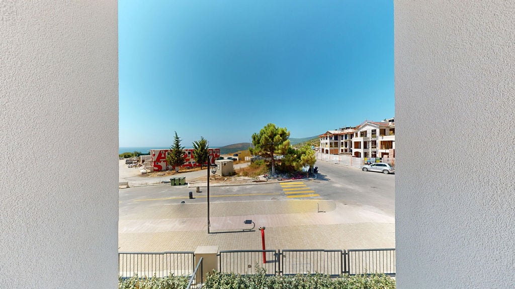 View from the balcony of an apartment in Luštica, Montenegro: a panorama of the residential complex under construction, the road, and the sea horizon.