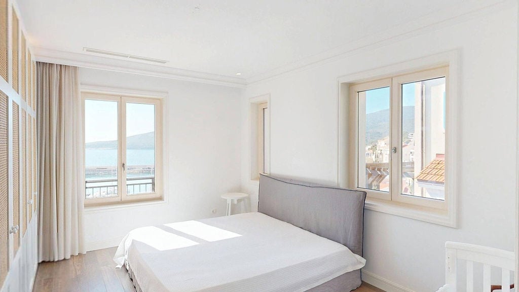 Bright bedroom in an apartment in Luštica, Montenegro: double bed, built-in wardrobe, and sea view from the window.