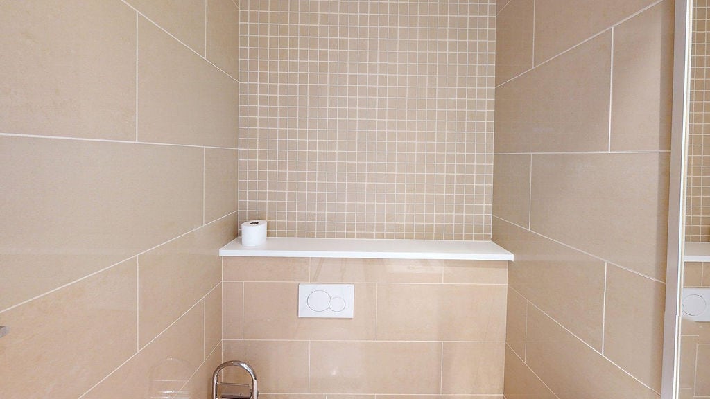 Modern bathroom with beige tiles and a built-in installation in an apartment, Luštica, Montenegro.