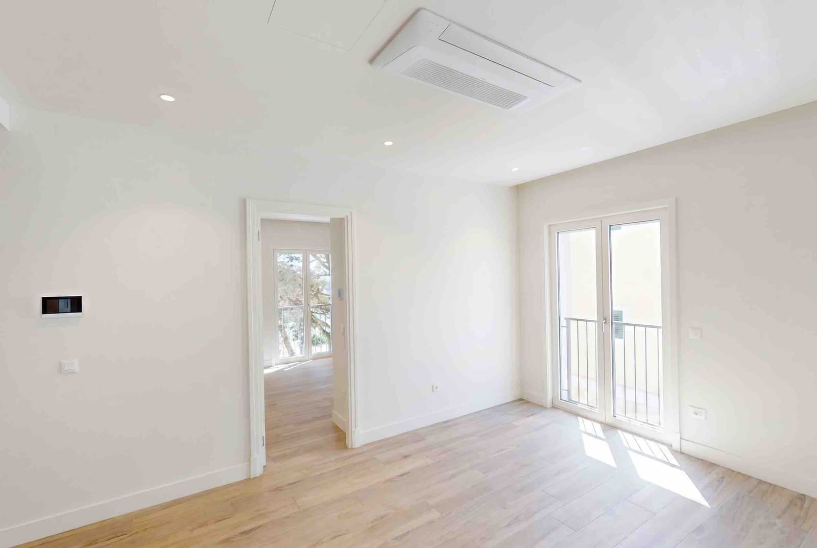 Bright living room with modern-style finishes in the Luštica residential complex, Montenegro: parquet flooring, built-in air conditioner, and balcony.