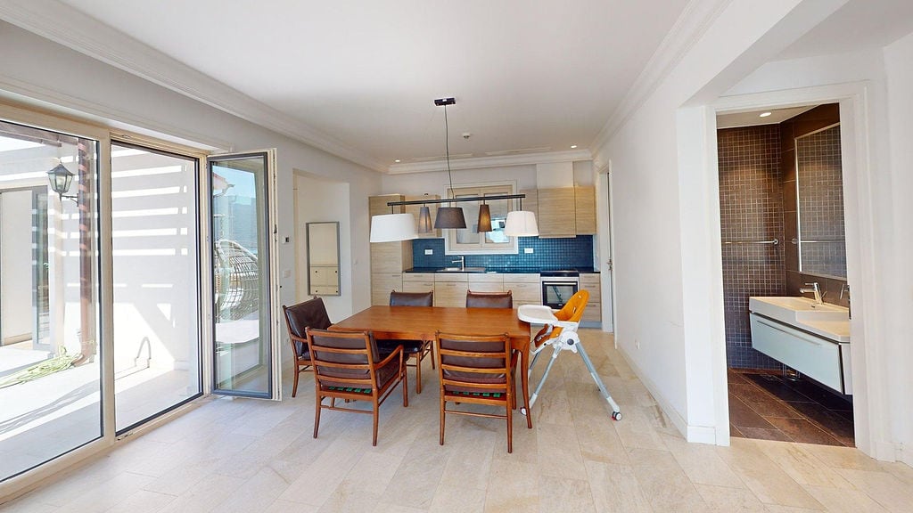 Modern kitchen-dining room with a wooden table and access to the terrace in an apartment, Luštica, Montenegro.