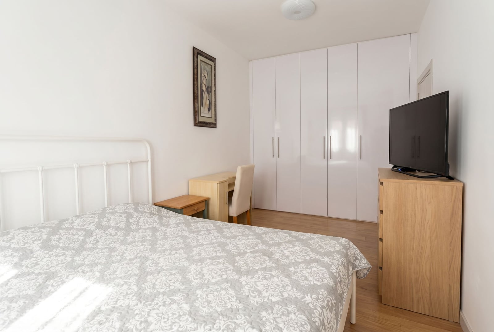 Bright bedroom with a white bed, wardrobe, and TV in an apartment for sale in Herceg Novi, Montenegro.