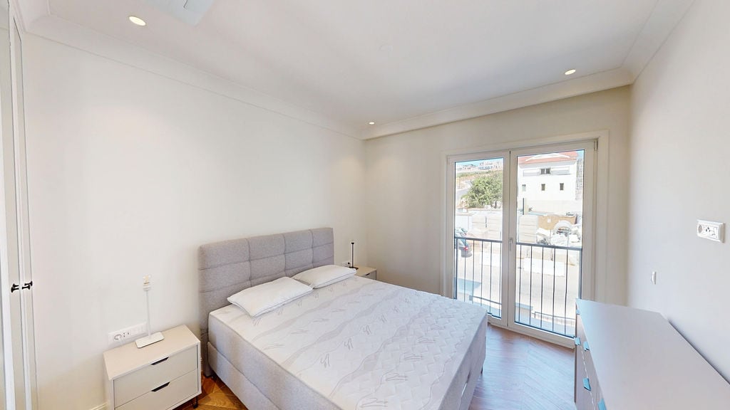 Bright bedroom with a double bed and balcony access in Luštica Bay apartments, Montenegro.