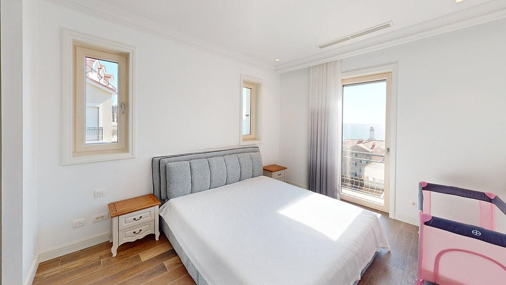 Bright bedroom with a double bed and sea view in the Luštica residential complex, Montenegro. Modern interior with a balcony.
