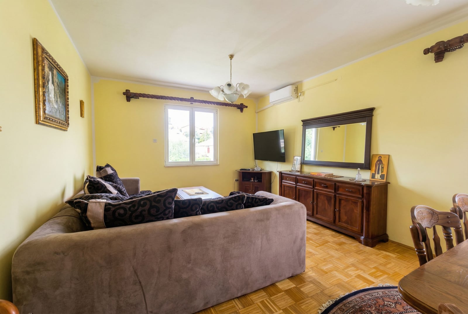 Cozy living room with a soft sofa, wooden furniture, and parquet flooring in a house for sale in Herceg Novi, Montenegro.