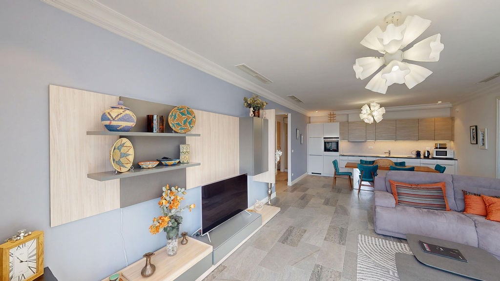 Modern living room with kitchen in an apartment, Luštica, Montenegro: stylish furniture, tiled floor, and designer chandeliers.