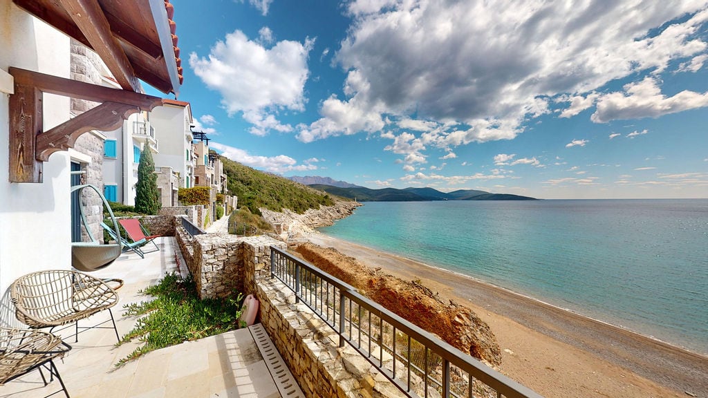 Terrace with wicker furniture and panoramic views of the sea and beach in the Luštica residential complex, Montenegro.