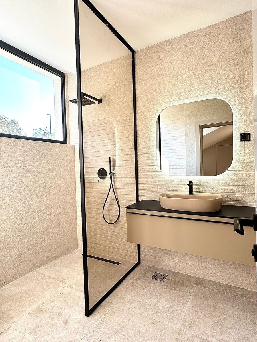Salle de bains moderne dans une villa à Kamenovo, Monténégro : douche avec profil noir, vasque à poser et miroir.
