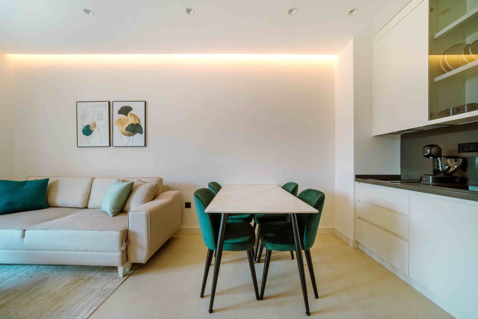 Modern living room with kitchen in an apartment, Bečići, Montenegro: beige sofa, dining table, and green chairs.