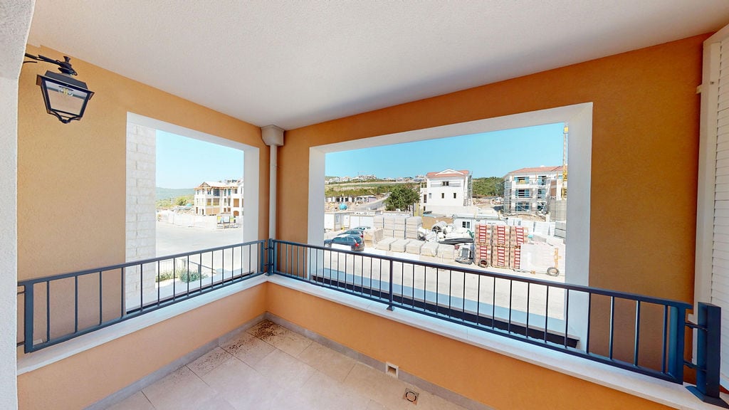 Open balcony with panoramic views of the construction site in Lustica Bay, Montenegro, featuring beige finishes and a metal railing.