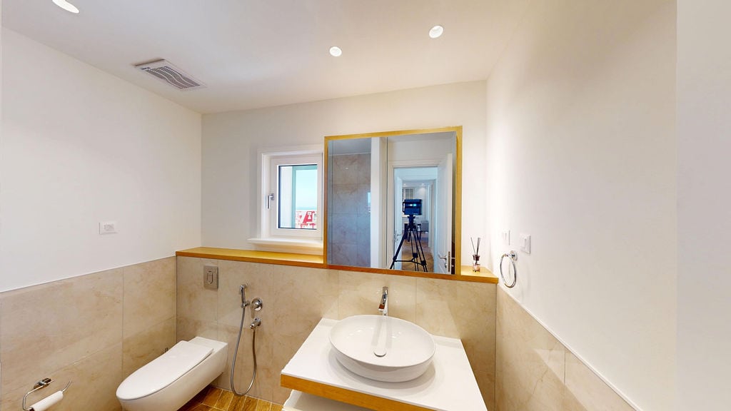 Modern bathroom with a countertop sink in an apartment in Luštica, Montenegro: light tiles and stylish design.
