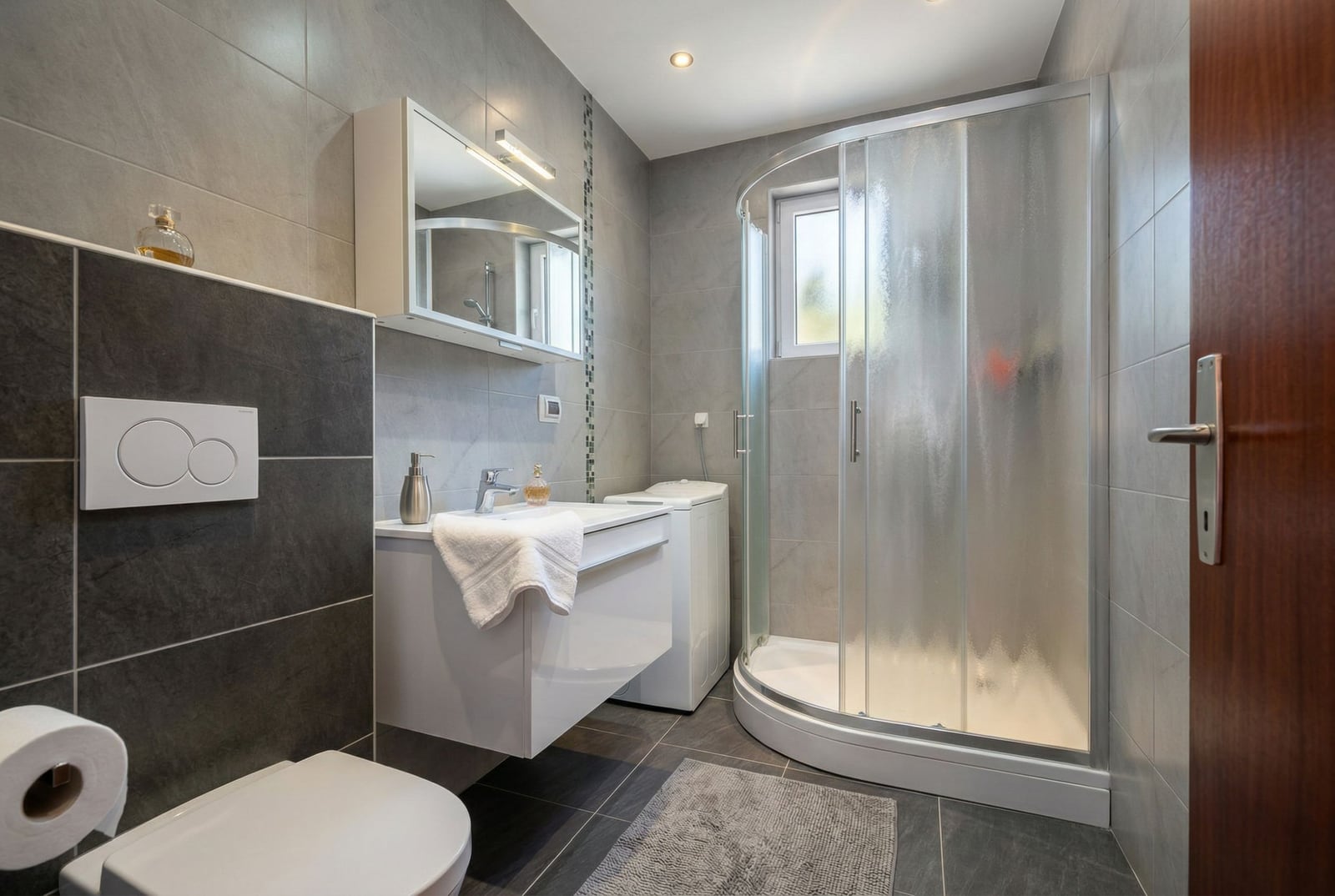 Modern bathroom in a house in Herceg Novi, Montenegro: shower cabin, vanity with sink, and washing machine.