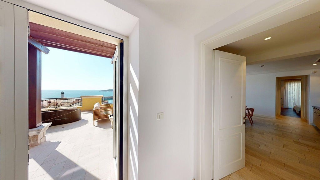Exit to a terrace with a sea view in a luxury apartment, Luštica, Montenegro: bright interior and lounge furniture.
