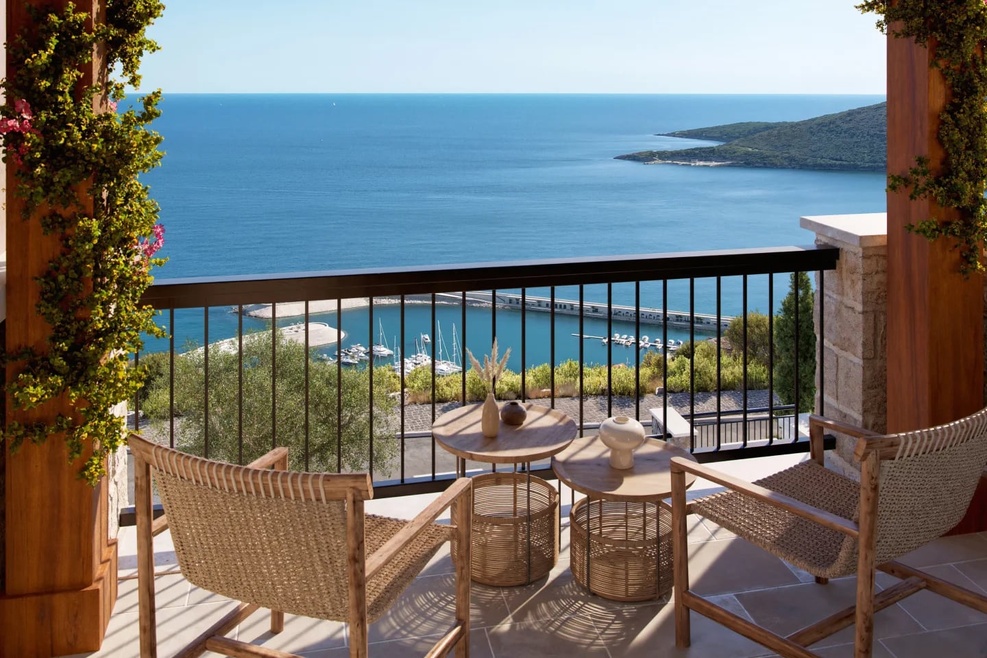 Terrace with sea and marina views in the Luštica residential complex, Montenegro: wicker furniture and stone finishes.