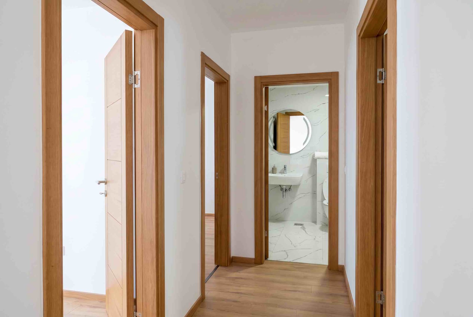 Bright hallway in an apartment, Pržno, Montenegro: view of a modern bathroom with marble-style finishes and wooden doors.