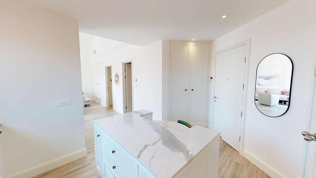 Interior of a modern apartment in Luštica, Montenegro: a bright hallway with a marble island and an oval mirror.