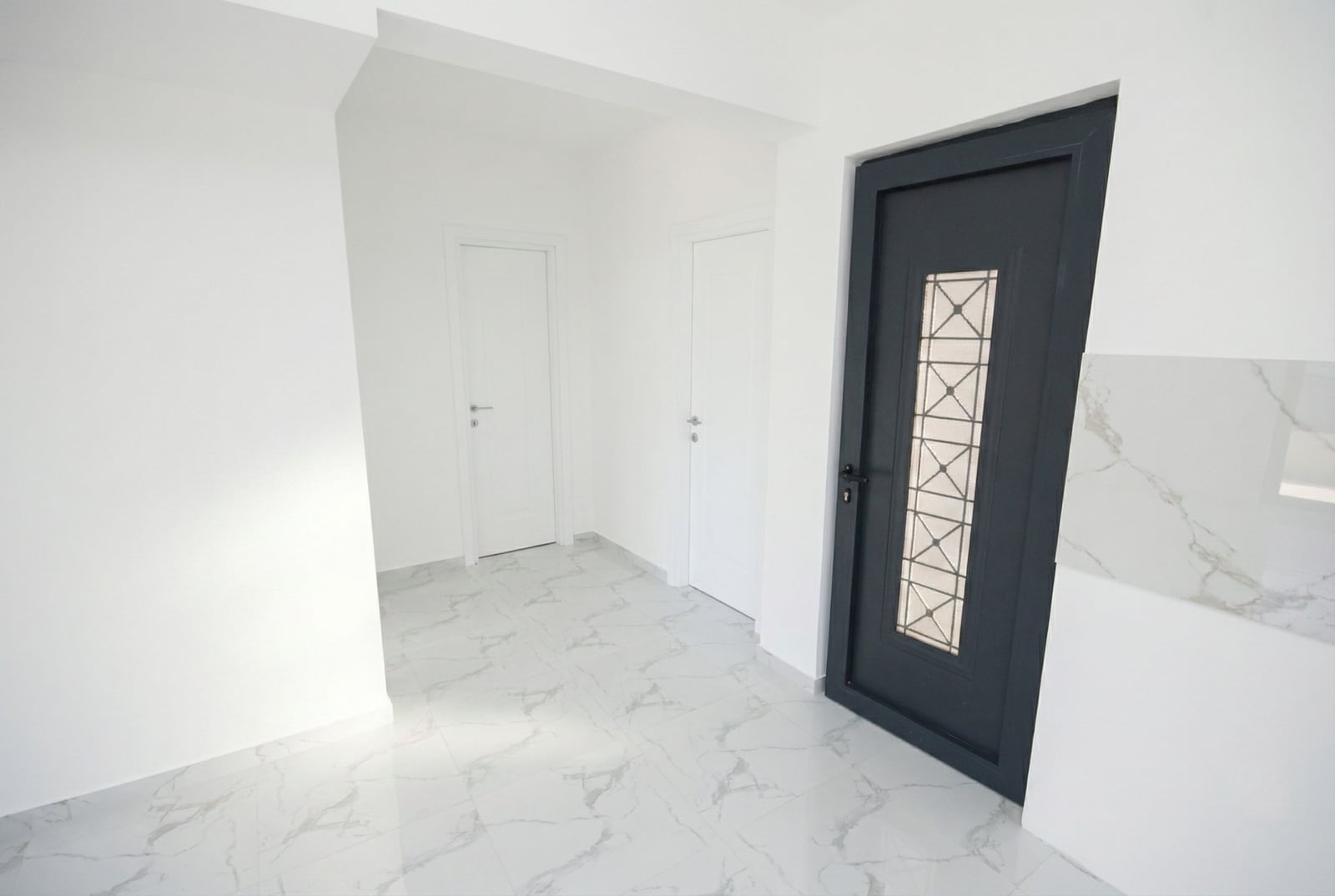Bright hallway with marble floor and dark front door in an apartment, Kumbor, Montenegro.