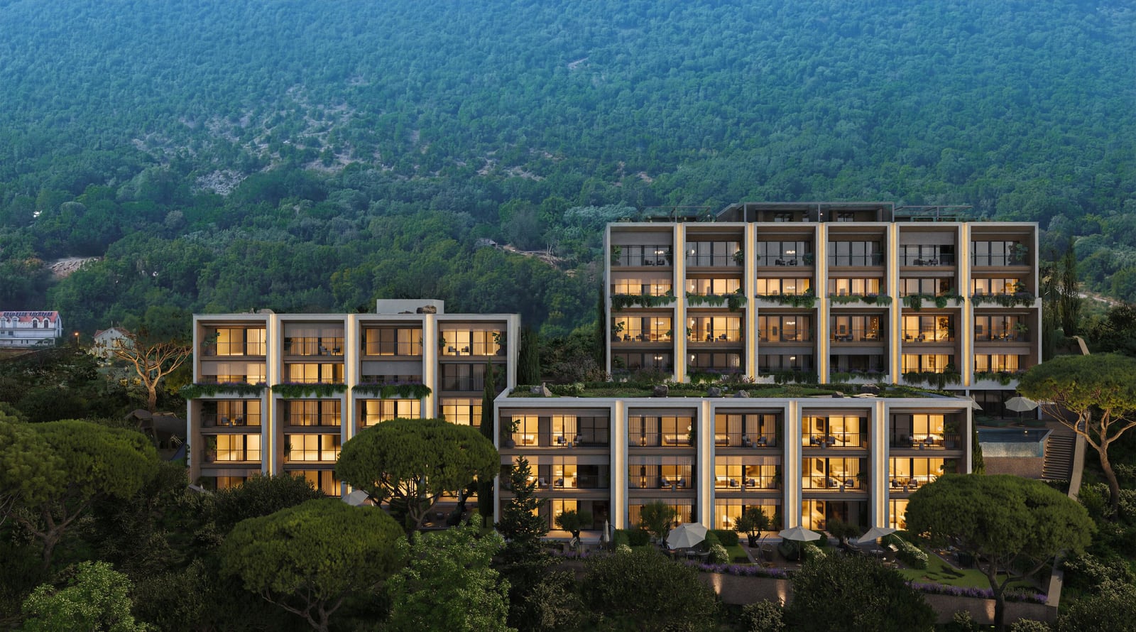 Modern residential complex in Kumbor, Montenegro: view of multi-story apartments with terraces against a backdrop of mountains and greenery.