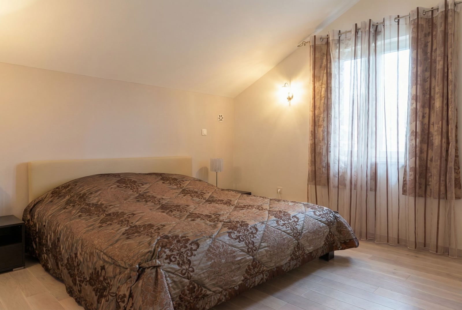 Cozy bedroom with a double bed in a house in Herceg Novi, Montenegro: sloped ceiling, bright interior.