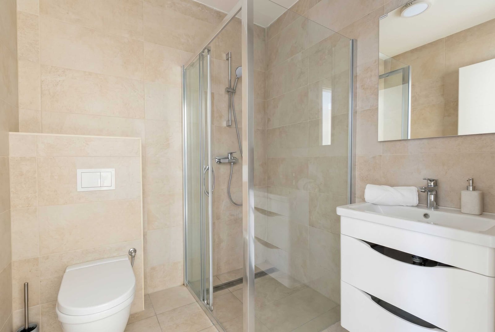 Modern bathroom with a shower cabin and light-colored tiles in an apartment for sale in Kavač, Montenegro.