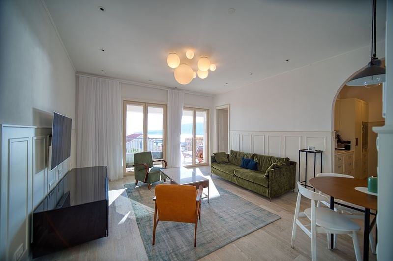 Bright living room with a green sofa and sea view in an apartment, Luštica, Montenegro. Modern interior with furniture.