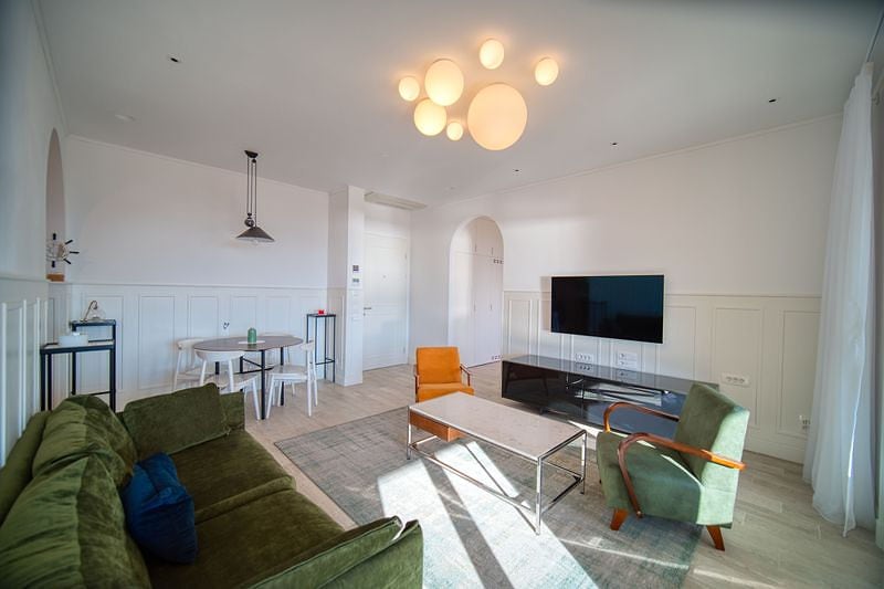 Modern living room with a green sofa and dining area in an apartment, Luštica Bay, Montenegro.